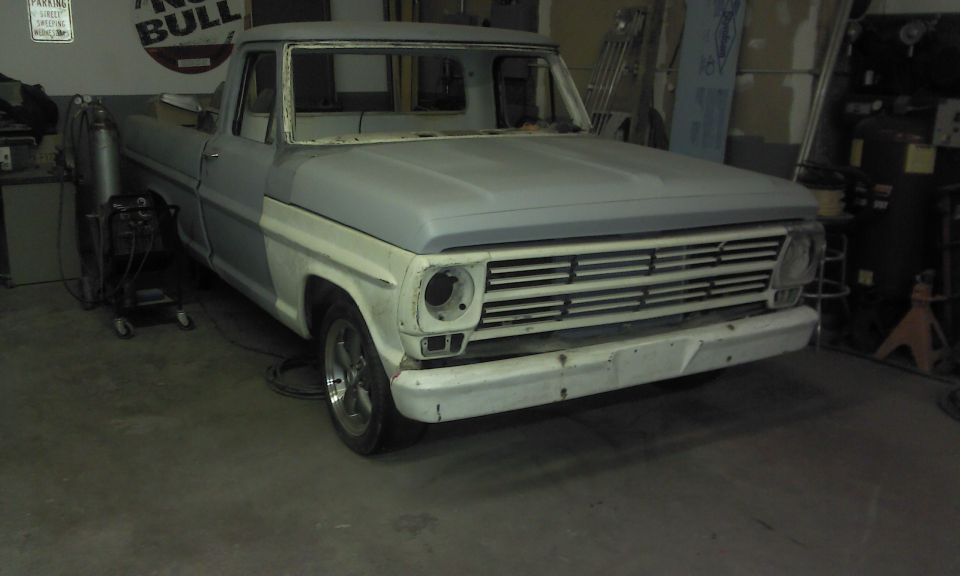 1967 Ford F-100 truck in primer, front 3/4 view, in a workshop