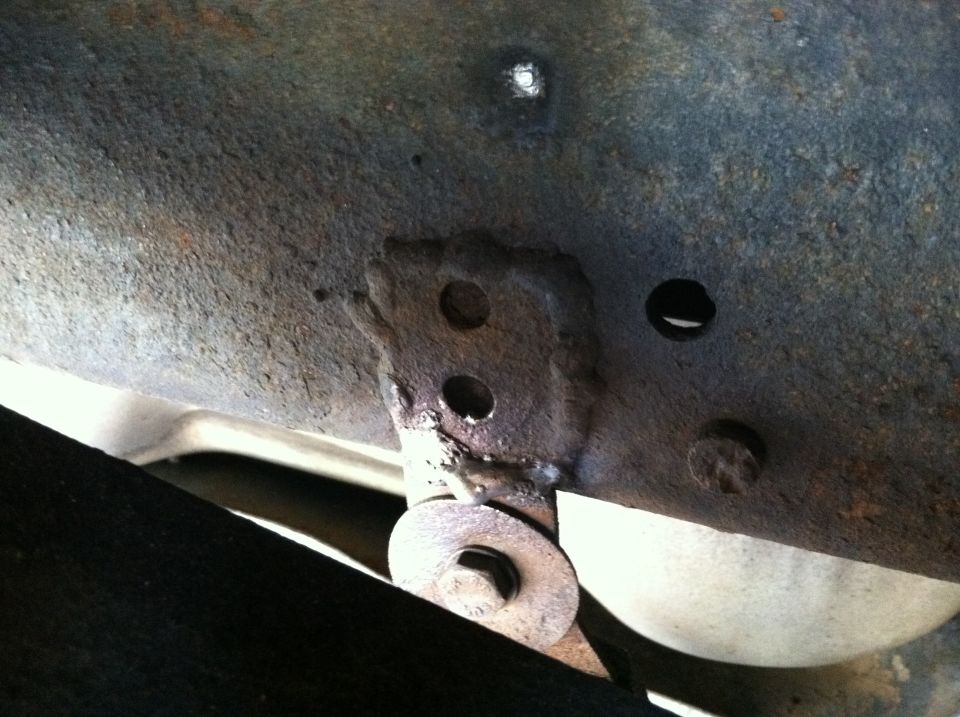 Close-up of rusted vehicle frame showing a mounting bracket and bolt