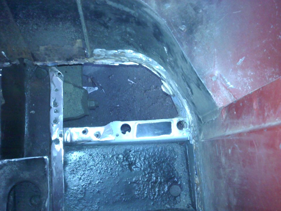 Red vehicle interior showing rust repair on wheel well and floor pan