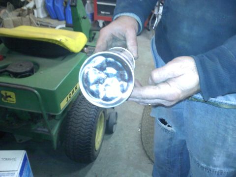 1978 Ford Bronco - A person holds a tube filled with ice next to a green John Deere lawn tractor.