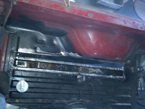 1978 Ford Bronco - Close-up view of the cargo area of a red vehicle, showing wear and tear on the floor and supports.