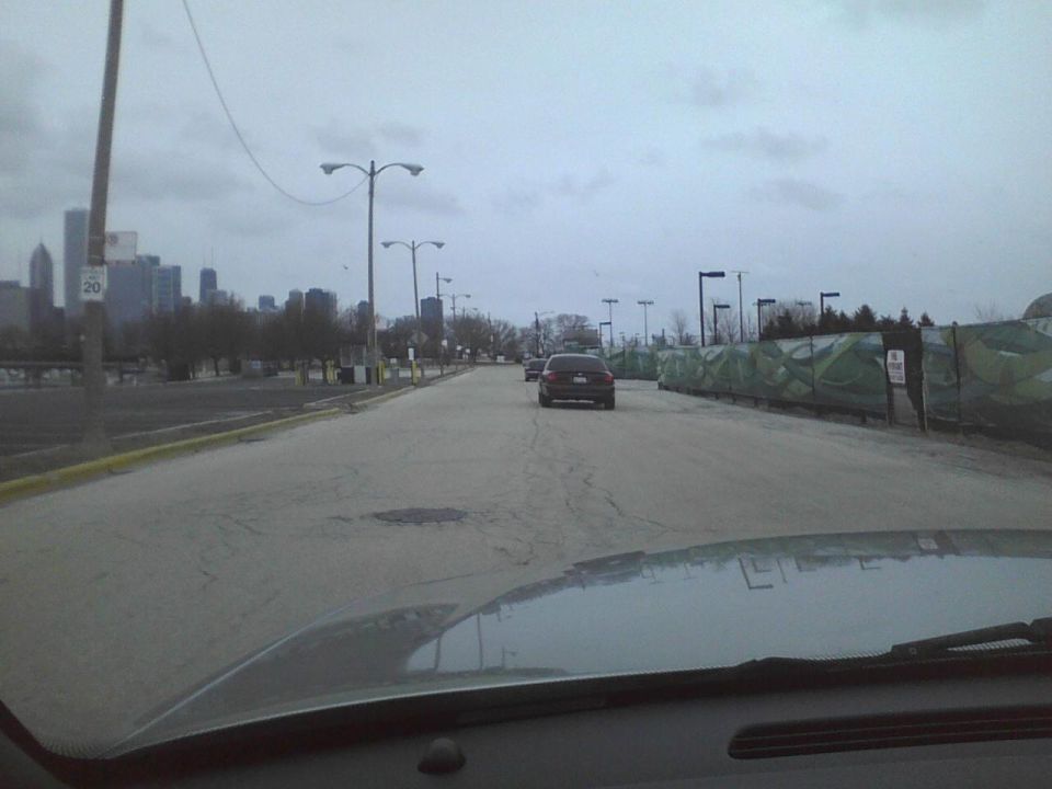 View from inside a car looking down a road towards a city skyline, with other cars on the road