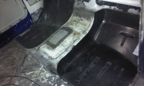 1967 Ford F-100 - The interior floor of a truck shows exposed metal and black plastic matting.