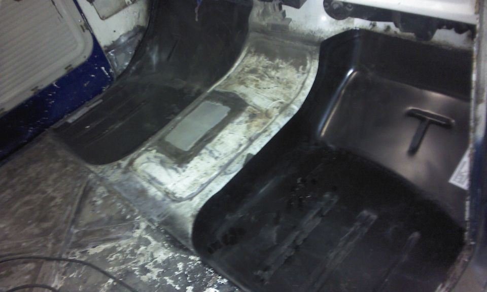 Truck interior floor with black plastic matting and exposed metal