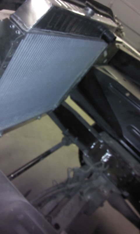1967 Ford F-100 - A close-up view of a vehicle's radiator and surrounding engine bay components, including hoses and mechanical linkages.