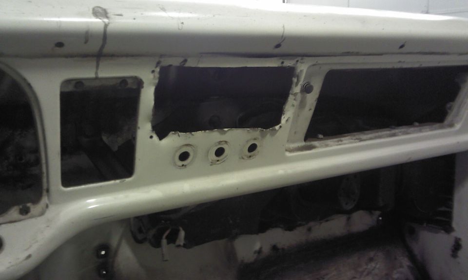 Close-up of a white vehicle's dashboard with large cutouts for gauges and radio