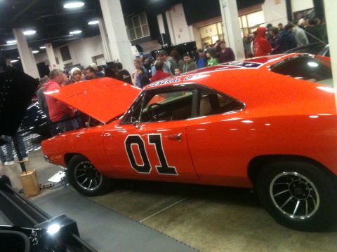2004 Ford Crown Victoria - An orange General Lee car with the number 01 on its side is displayed indoors with people around.