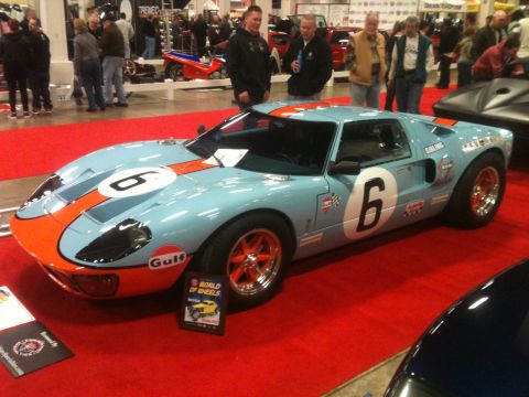 2004 Ford Crown Victoria - A Gulf-liveried Ford GT40 is displayed indoors on a red carpet, with spectators in the background.