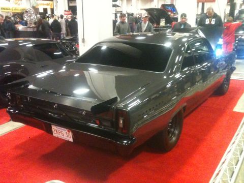 2004 Ford Crown Victoria - A dark gray coupe with a spoiler and custom plate is displayed on a red carpet at an auto show.