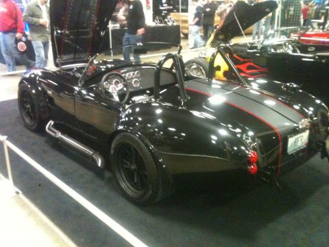 2004 Ford Crown Victoria - A black sports car with racing stripes and side pipes is parked indoors.