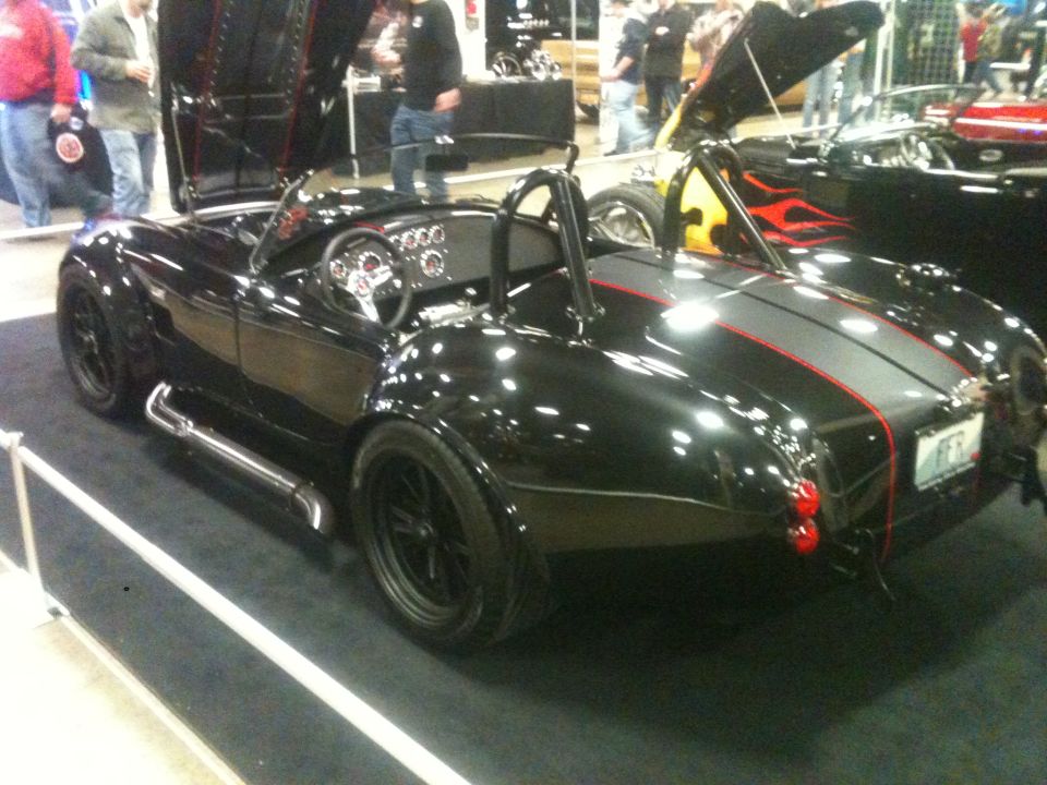 Black sports car with side exhaust pipes and racing stripes on display