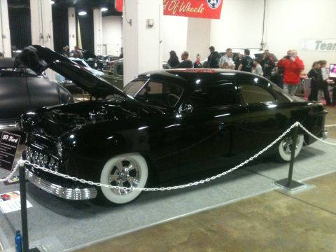 2004 Ford Crown Victoria - A customized 1950 Ford coupe is displayed with its hood open at a car show.