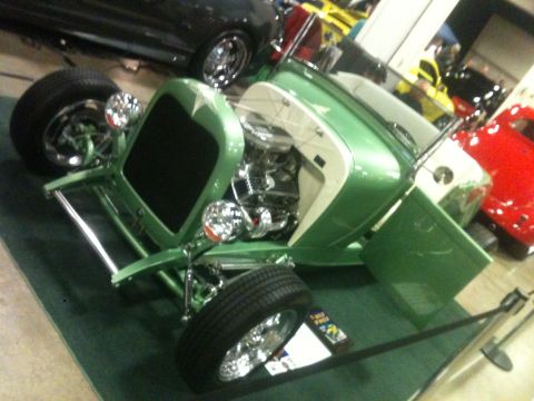 2004 Ford Crown Victoria - A custom green hot rod is displayed with its door open, revealing the engine. Other vehicles are visible in the background.