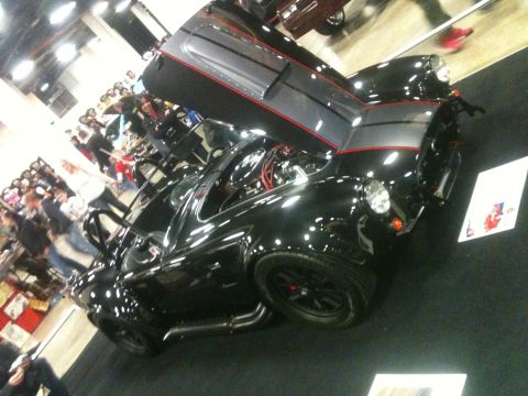 2004 Ford Crown Victoria - A black sports car with its hood open, revealing the engine, is displayed indoors.