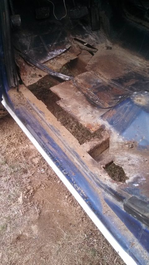 1979 Ford Bronco - The interior of a vehicle displays significant rust and damage to the floor panels.