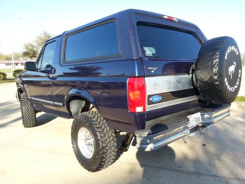 1995 Ford Bronco - This lifted Ford Bronco is shown from the rear-three-quarter angle, with a spare tire mounted on the back.