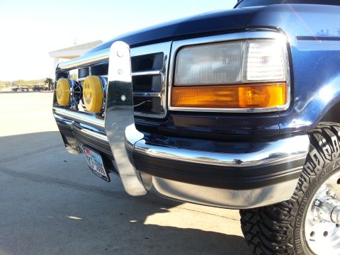 1995 Ford Bronco - Front view of a blue Ford truck, modified with a bull bar and distinctive yellow lights.