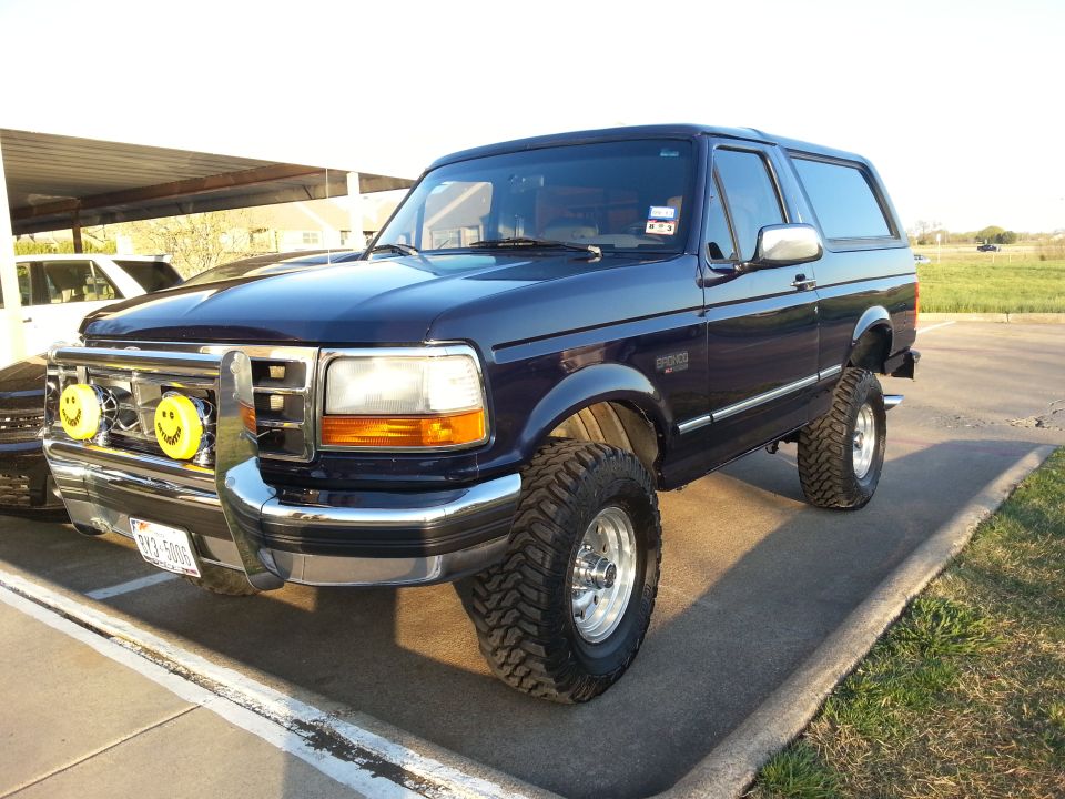 Dark blue Ford Bronco with smiley face fog lights and lifted suspension