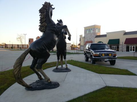 1995 Ford Bronco - A 1995 Ford Bronco is parked in front of a commercial building, with two large horse statues in the foreground.