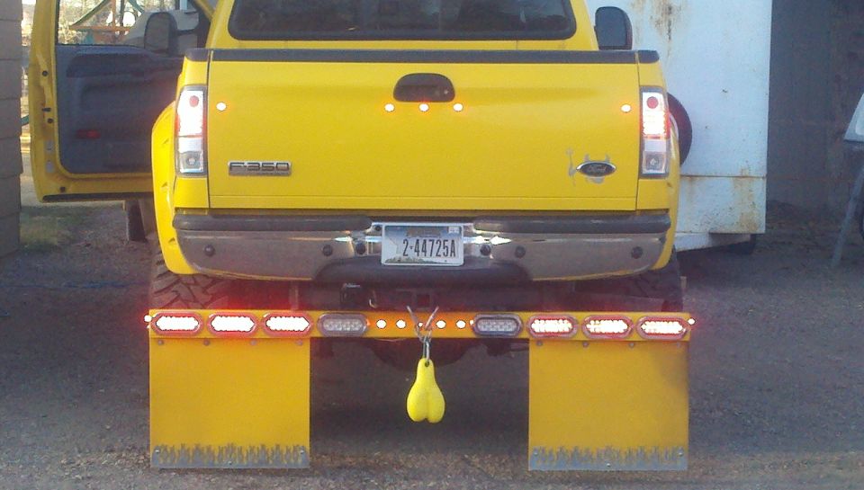 Rear of yellow Ford F-350 with LED light bar, yellow mud flaps, and lit tail lights