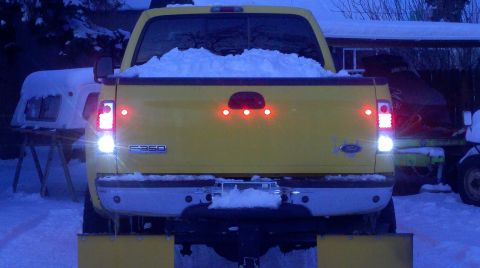 2005 Ford F-350 - Rear view of a yellow 2005 Ford F-350 pickup truck covered in snow, equipped with a snow plow.