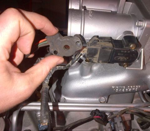1994 Ford Bronco - Close-up of a Ford throttle position sensor being handled near an engine part.