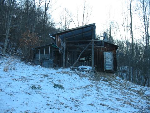 1992 Ford Bronco - An old, weathered barn stands on a snow-covered slope, surrounded by bare trees.