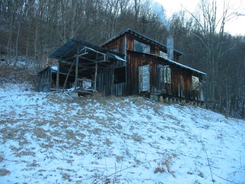 1992 Ford Bronco - An old, weathered cabin sits on a snowy slope, smoke rising from its chimney.