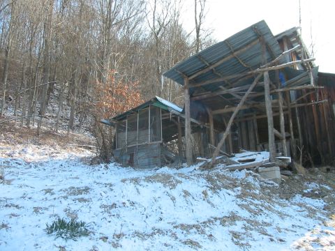 1992 Ford Bronco - Abandoned wooden structures stand in a snowy, wooded landscape during winter.