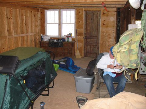 1992 Ford Bronco - A person sits in a chair in a room with wood paneling, a tent, and camping equipment.