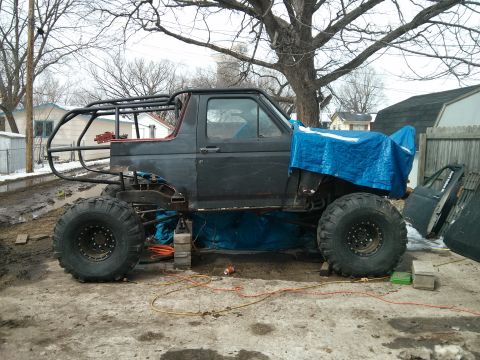 1986 Ford Bronco - This heavily modified SUV is undergoing some work, with a custom roll cage and large off-road tires visible.