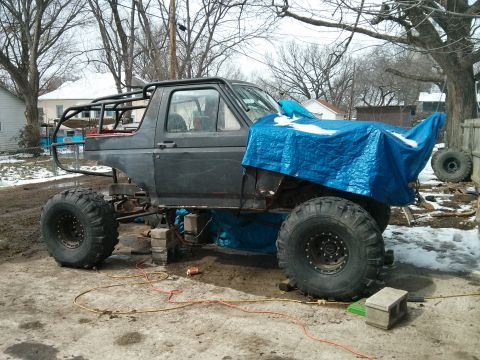 1986 Ford Bronco - This modified Ford Bronco sits on blocks with a roll cage and oversized tires, awaiting further work.