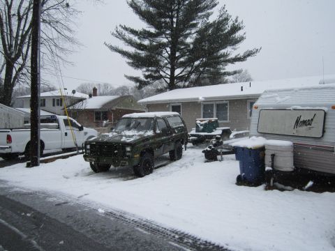 1985 Chevrolet Blazer - A dark green SUV is parked in a snowy yard next to a white pickup truck and a trailer.