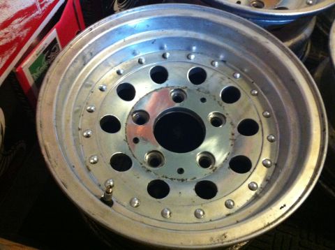 1992 Ford F-150 - A single aluminum wheel with a multi-lug pattern is shown, with other wheels stacked in the background.