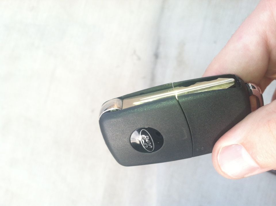 Hand holding a Ford key fob with the Ford logo visible