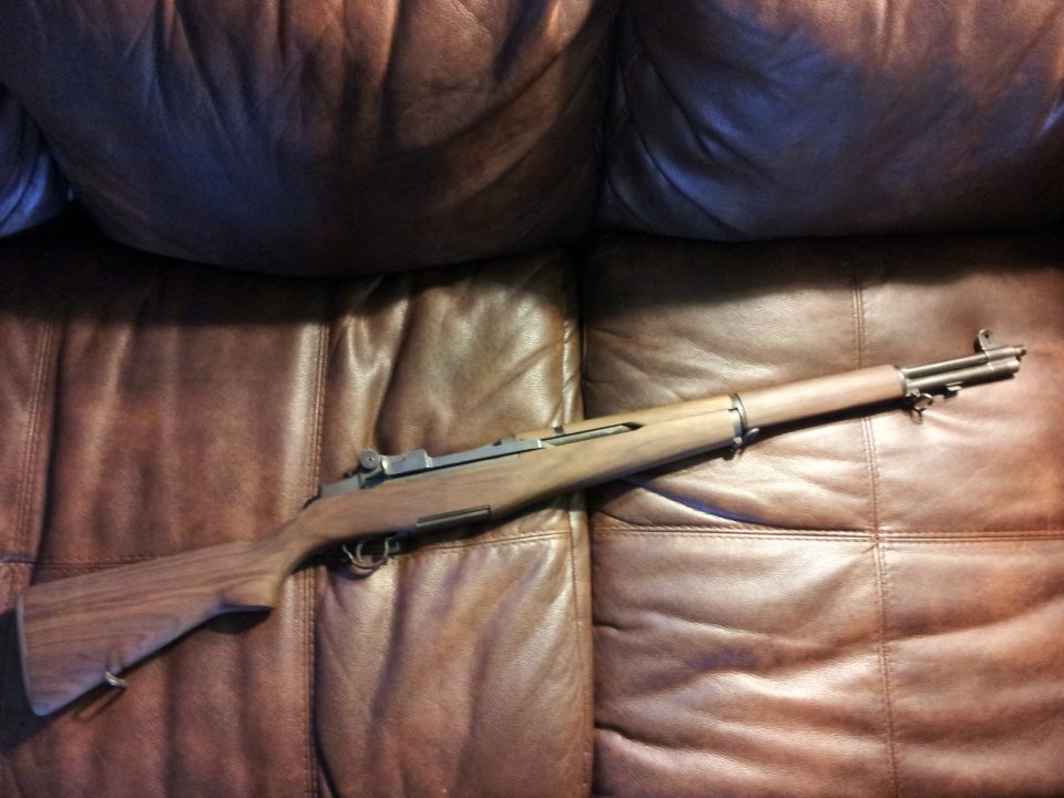 M1 Garand rifle on a brown leather couch
