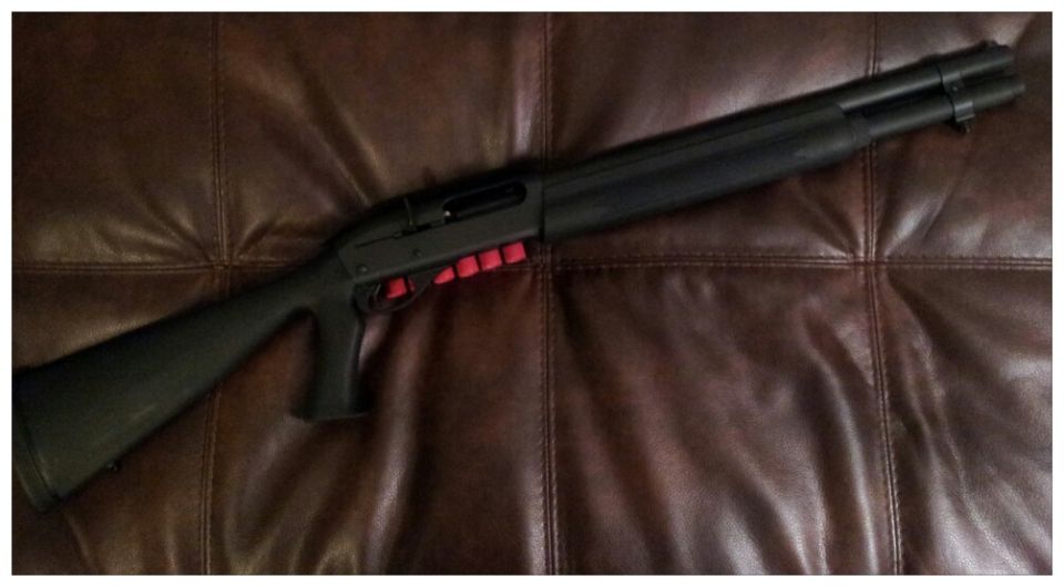 Black shotgun with red shell holder on brown leather couch