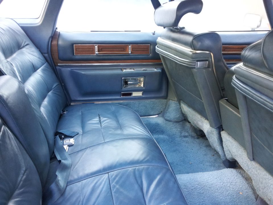 Blue leather rear seats and door panel with wood trim. A seatbelt is visible