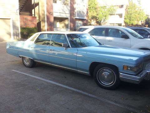 2008 Subaru Legacy - A light blue 1975 Cadillac Sedan de Ville is parked in a lot next to a white SUV.