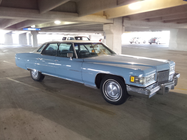 Light blue 1974 Cadillac sedan with a vinyl roof, seen from the front-right in a parking garage