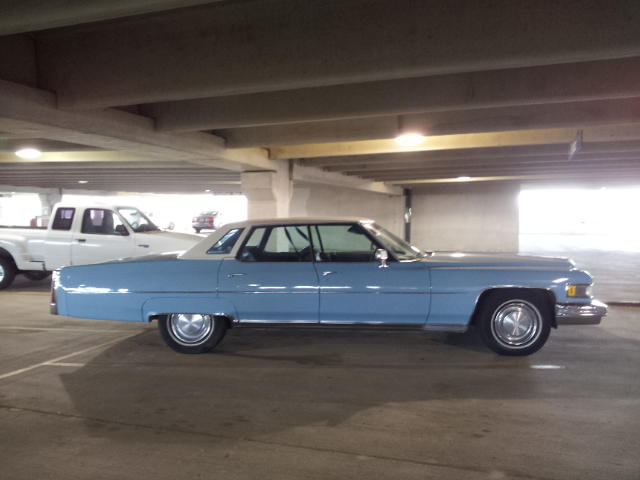 Side view of a light blue 1970s Cadillac sedan parked in a garage