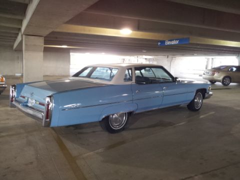 2008 Subaru Legacy - This blue Cadillac sedan is parked in a garage with an elevator sign overhead.
