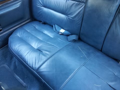 2008 Subaru Legacy - The interior of a vehicle shows a blue leather rear seat with a seatbelt and visible scratches on the upholstery.