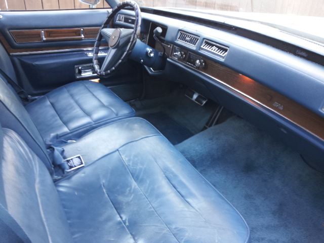 Blue leather interior of a vintage car, showing front seats, dashboard, and steering wheel