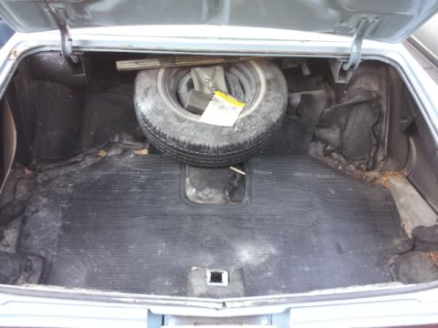 2008 Subaru Legacy - The interior of a car's trunk shows a spare tire and a worn rubber mat.