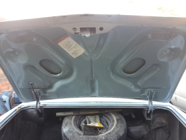 Open car trunk showing spare tire and some stickers on the underside of the hood