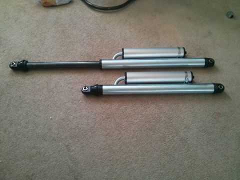 1986 Ford Bronco - Two shock absorbers are shown laid out on a carpeted floor, likely for installation or comparison.