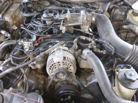 1998 Ford Crown Victoria - The engine bay of a vehicle is shown, various components like the alternator and intake system.