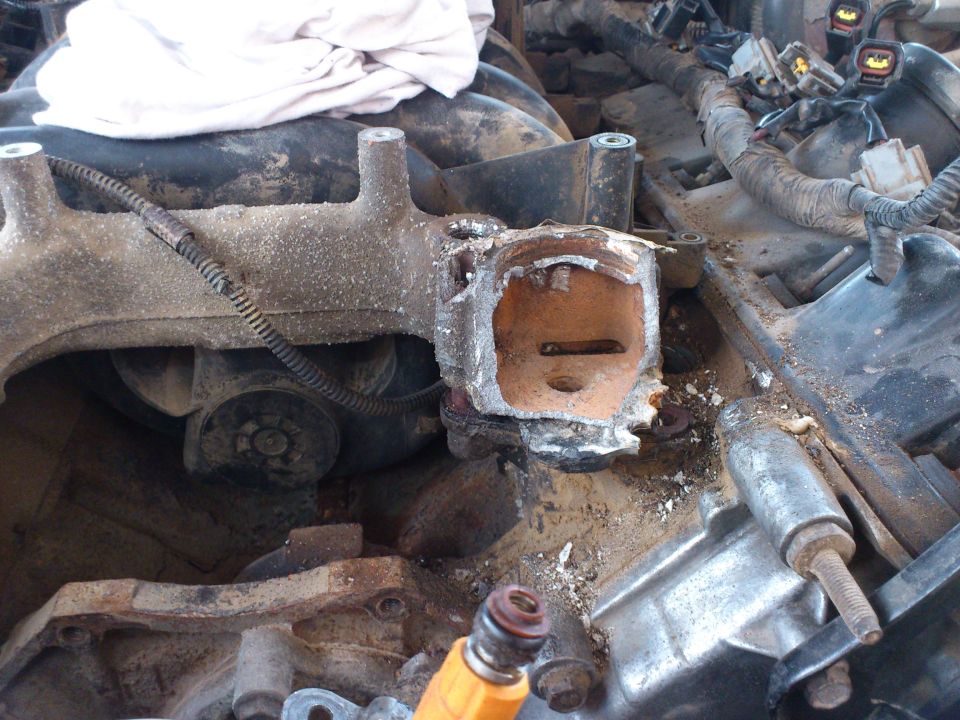 Damaged engine intake manifold with debris and a fuel injector visible