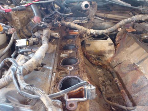 1998 Ford Crown Victoria - Close-up view of a corroded engine intake manifold, showing wiring and internal components.